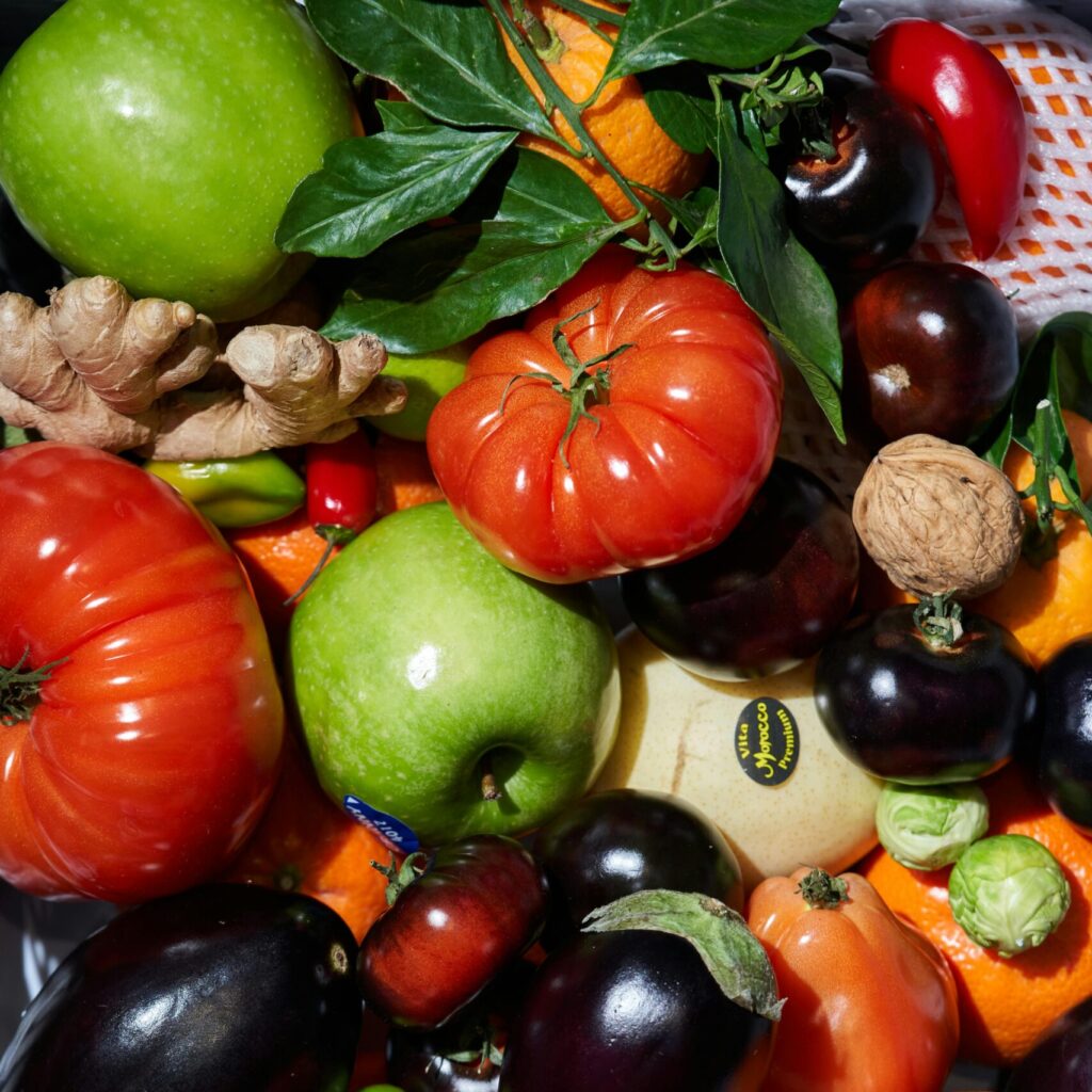 A colorful mix of fresh fruits and vegetables, including tomatoes, peppers, and ginger, photographed in London.