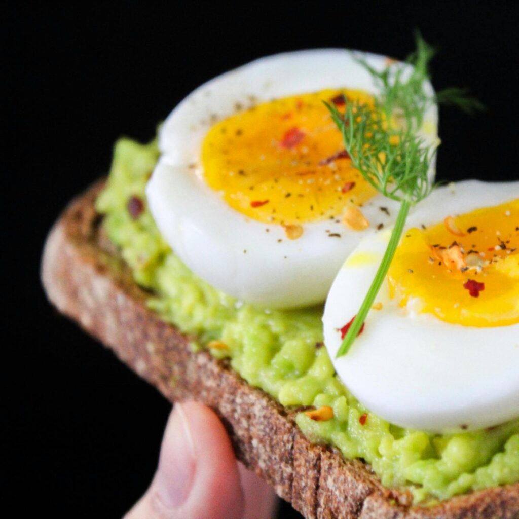 A delicious and healthy avocado toast topped with soft-boiled eggs, perfect for a nutritious breakfast.