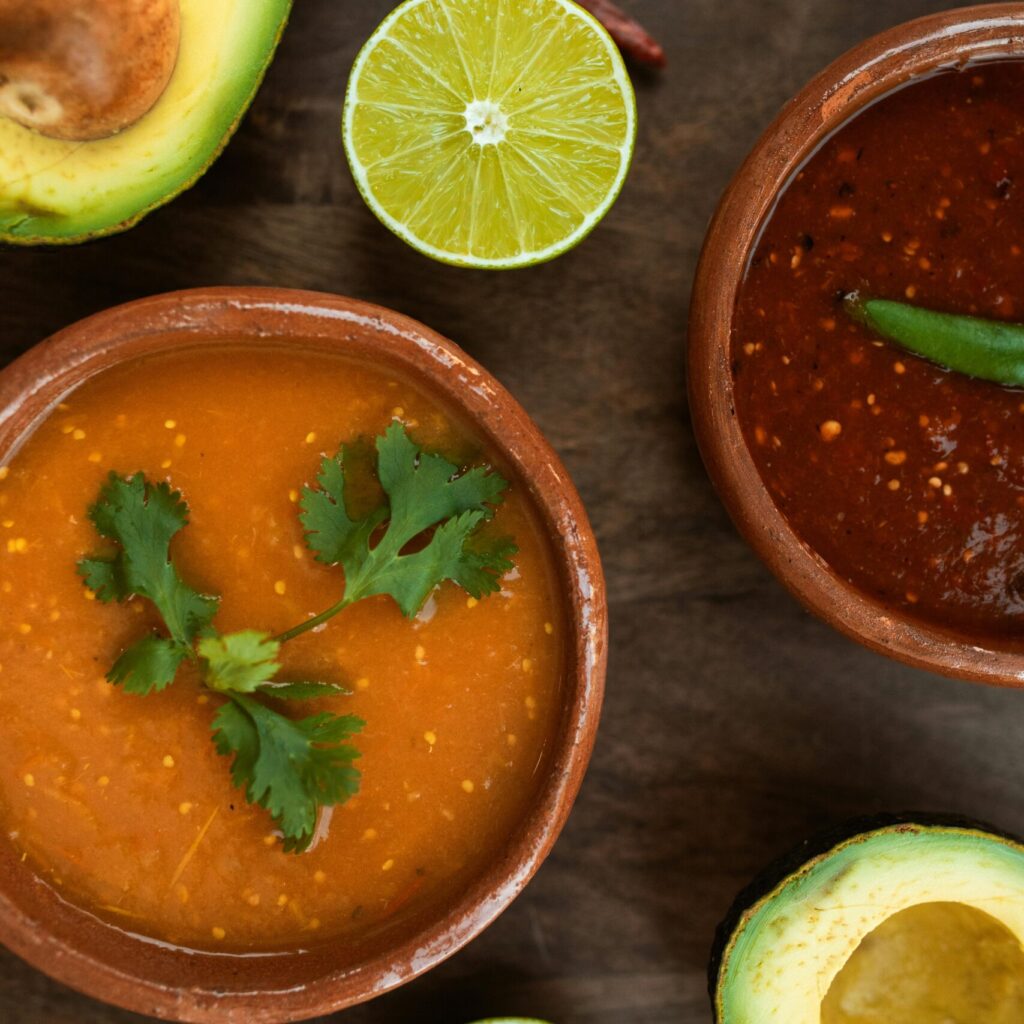 Top view of Mexican salsas with avocado and lime slices, vibrant and delicious.
