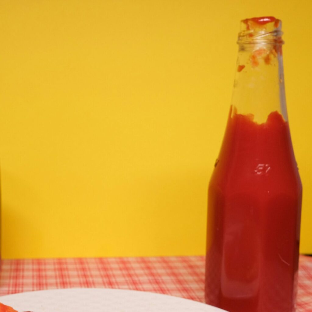 Sizzling pepperoni pizza slice with soda and ketchup against a vibrant yellow backdrop.