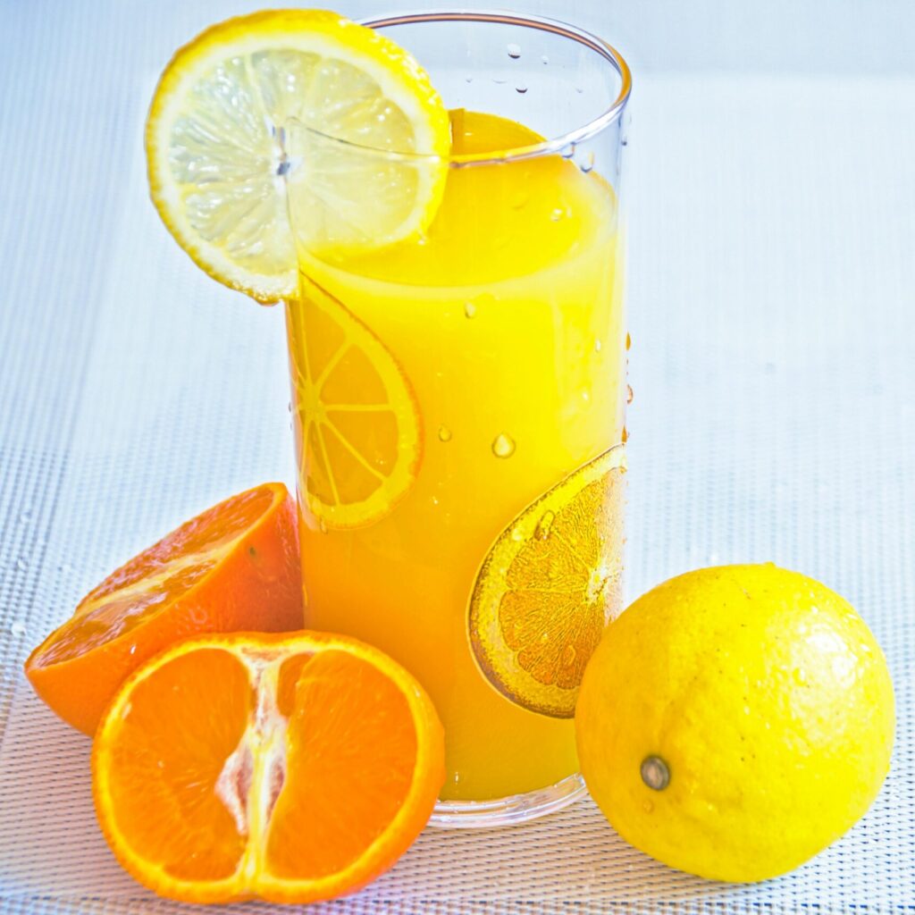 Vibrant citrus juice in a glass with fresh orange and lemon slices, offering a refreshing taste of summer.